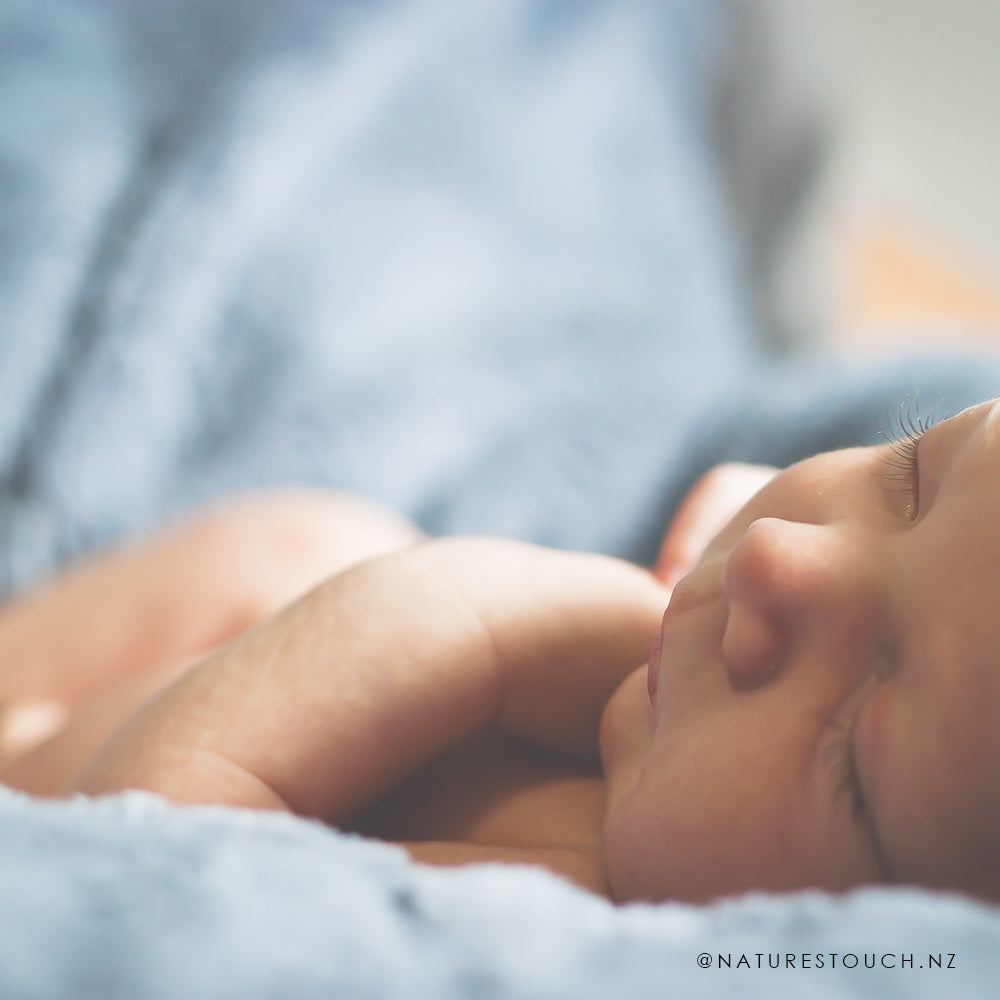 Sleepy baby gently resting on a soft blanket after receiving baby massage