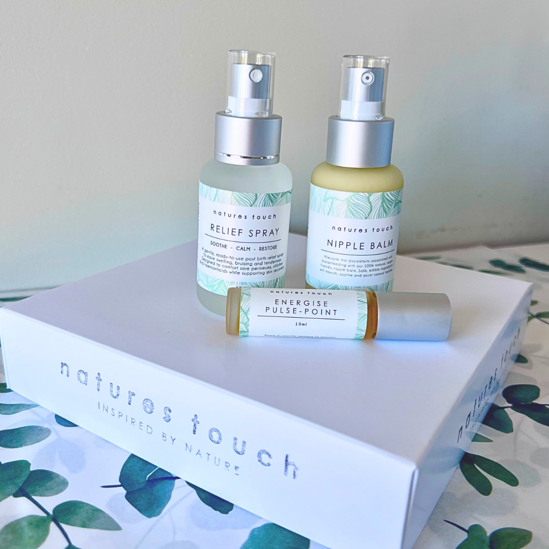 A set of Natures Touch postpartum care products: a Relief Spray bottle, a Nipple Balm bottle, and an Energy aromatherapy Pulse Point 