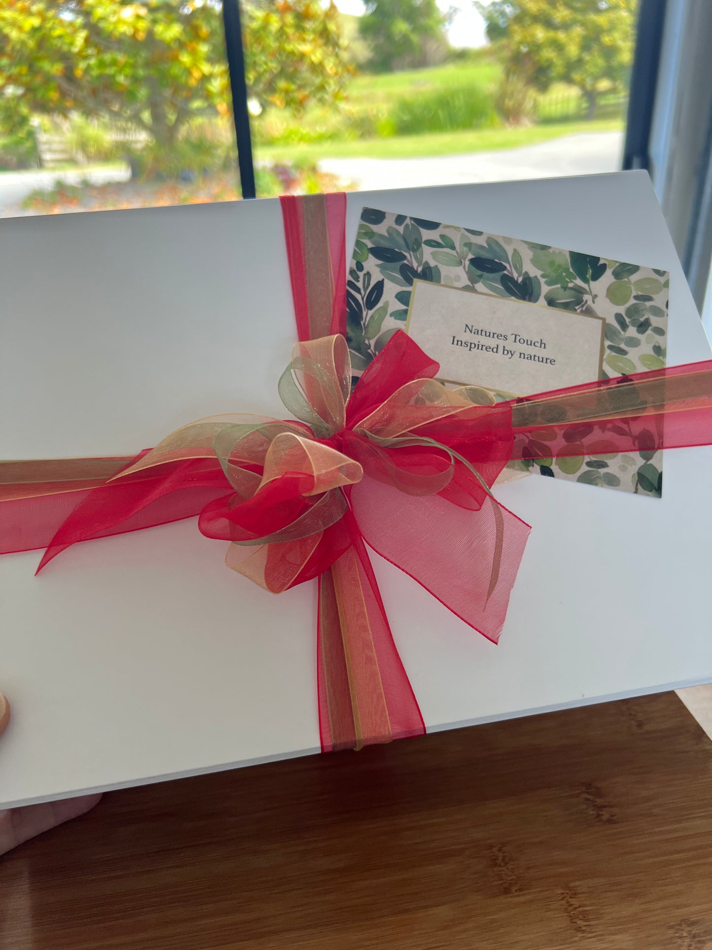 Luxurious Christmas gift box for new mum, tied with a red and gold ribbon, featuring a gift card. Containing three natural skincare products to support postnatal recovery